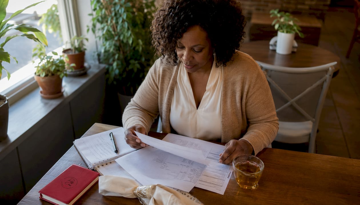 Woman reviewing mortgage refinance papers at table